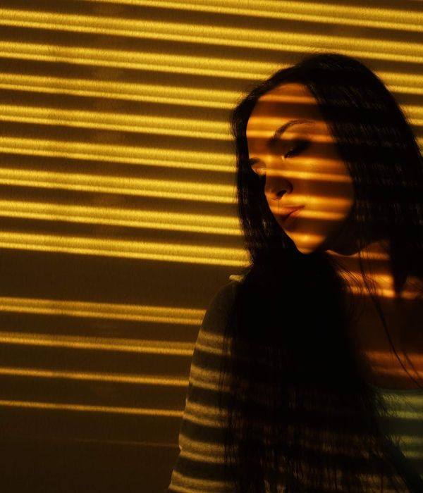 Woman in a calm yoga pose in a dark room with golden light.